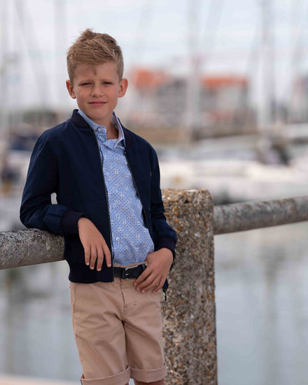 Coole Bomberjacke mit blau bedrucktem Hemd und beigen Bermudashorts