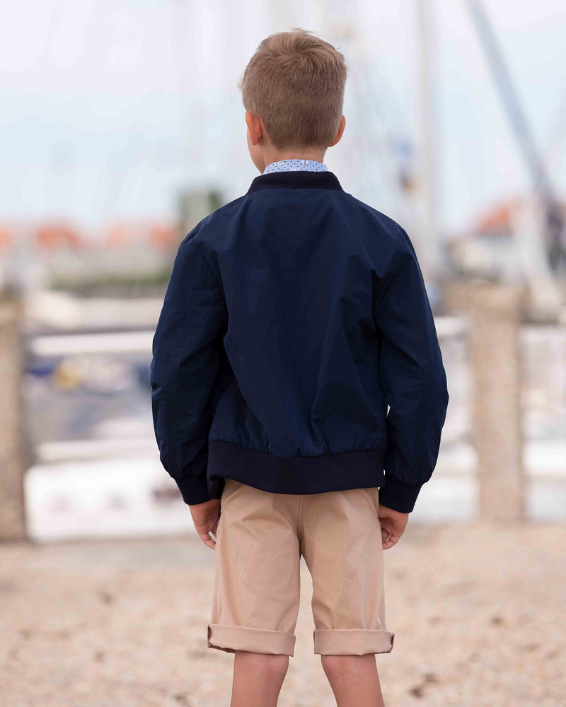 Coole Bomberjacke mit blau bedrucktem Hemd und beigen Bermudashorts